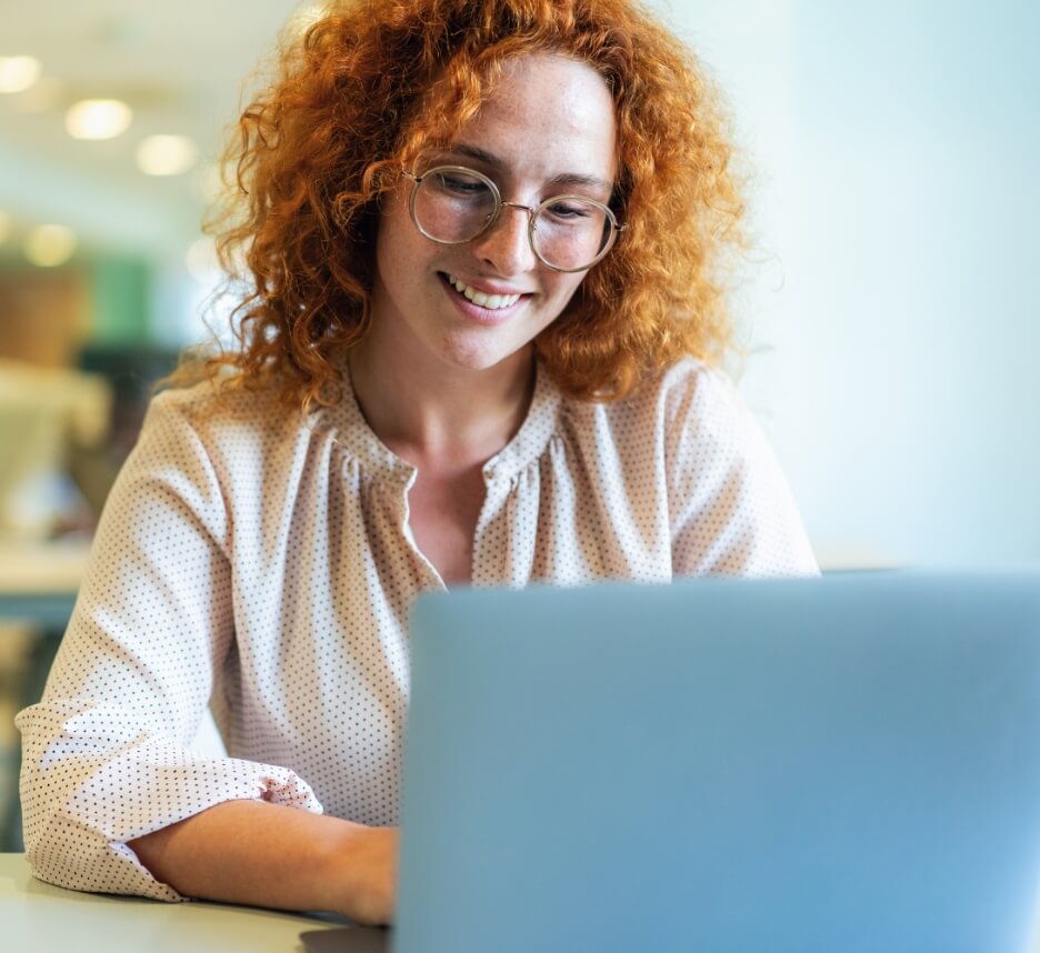 woman with red hair looking at laptop